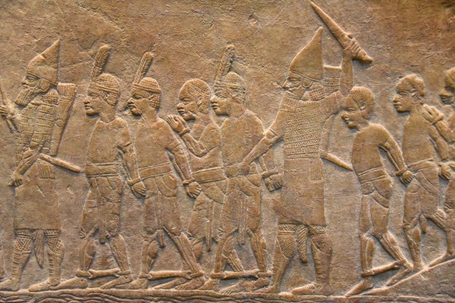 上图：主前645-635年从尼尼微出土的亚述浮雕，描绘主前667年亚述袭击埃及孟斐斯的一座堡垒，第二十五王朝法老特哈加（Taharqa）的古实士兵穿着短裙、赤着脚，被戴上手铐和脚镣掳走。收藏于大英博物馆。